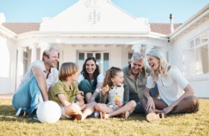 A multi-generational family relaxing on the lawn in front of their home.