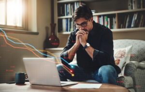 Investor reviewing a laptop with declining market charts overlaid