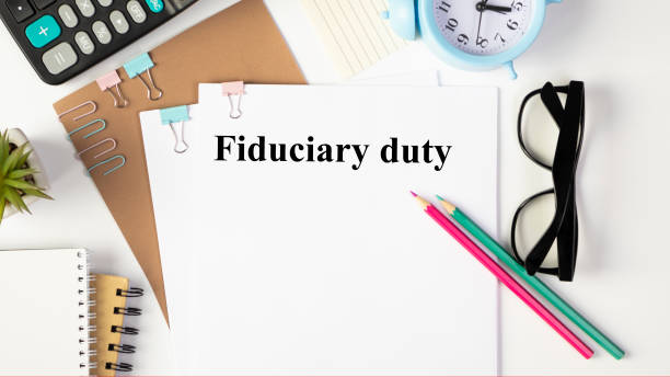 A sheet of paper labeled Fiduciary duty on a desk with a calculator and glasses.