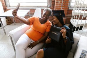 A graduate in cap and gown celebrating with a family member, representing Texas families choosing between a 529 savings plan and prepaid tuition