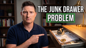 Stephen Nelson points to an open drawer containing financial papers, coins, a model home, and a Bitcoin token beneath the words “The Junk Drawer Problem.”